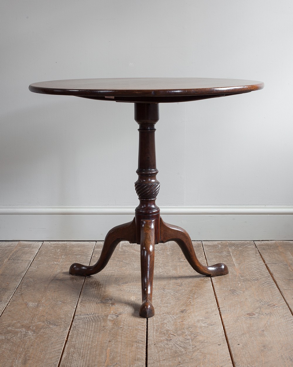 A George III mahogany tripod table featuring a circular top supported by a turned pedestal column with spiral carving and three cabriole legs. View X