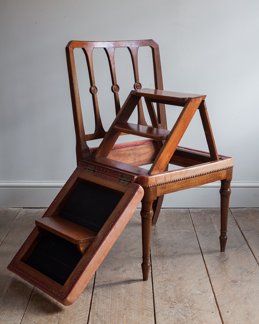 A 19th-century mahogany metamorphic chair shown unfolded into a set of four wooden library steps.