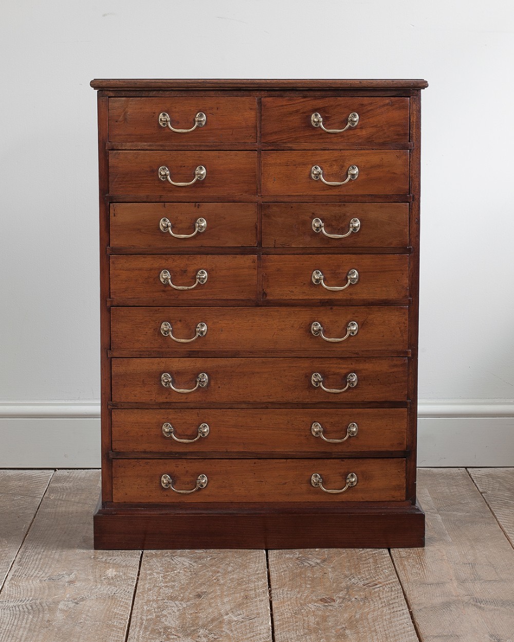 A tall 19th-century mahogany bank of drawers featuring eight tiers of small and wide drawers with brass handles, resting on a solid plinth base. View II