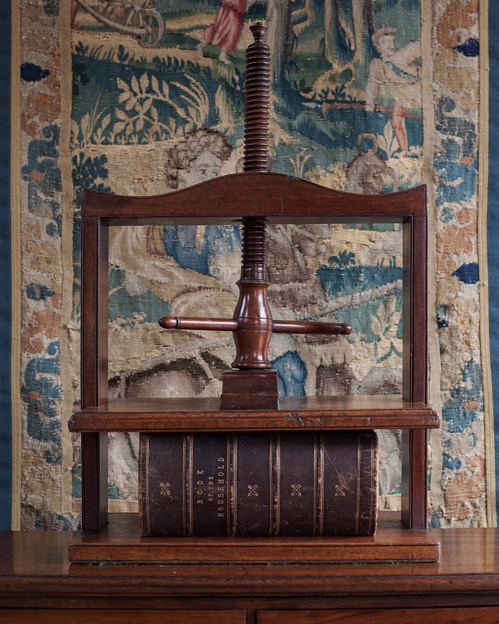 A Georgian mahogany wooden book press featuring a central hand-turned threaded screw mechanism and platen resting on a solid timber base.