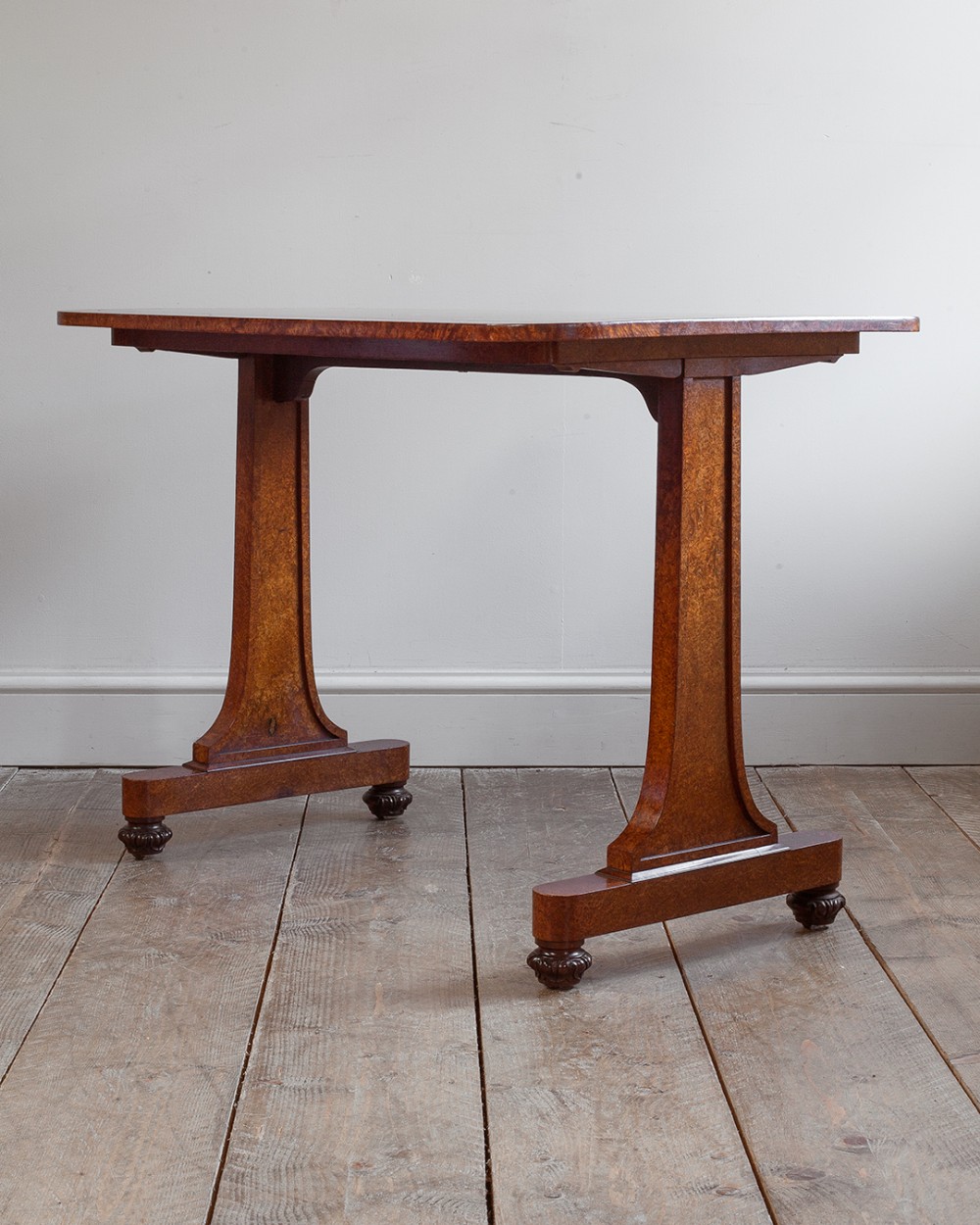 A Regency mahogany writing table with a polished rectangular top resting on two flared trestle end supports and gadrooned carved feet.
