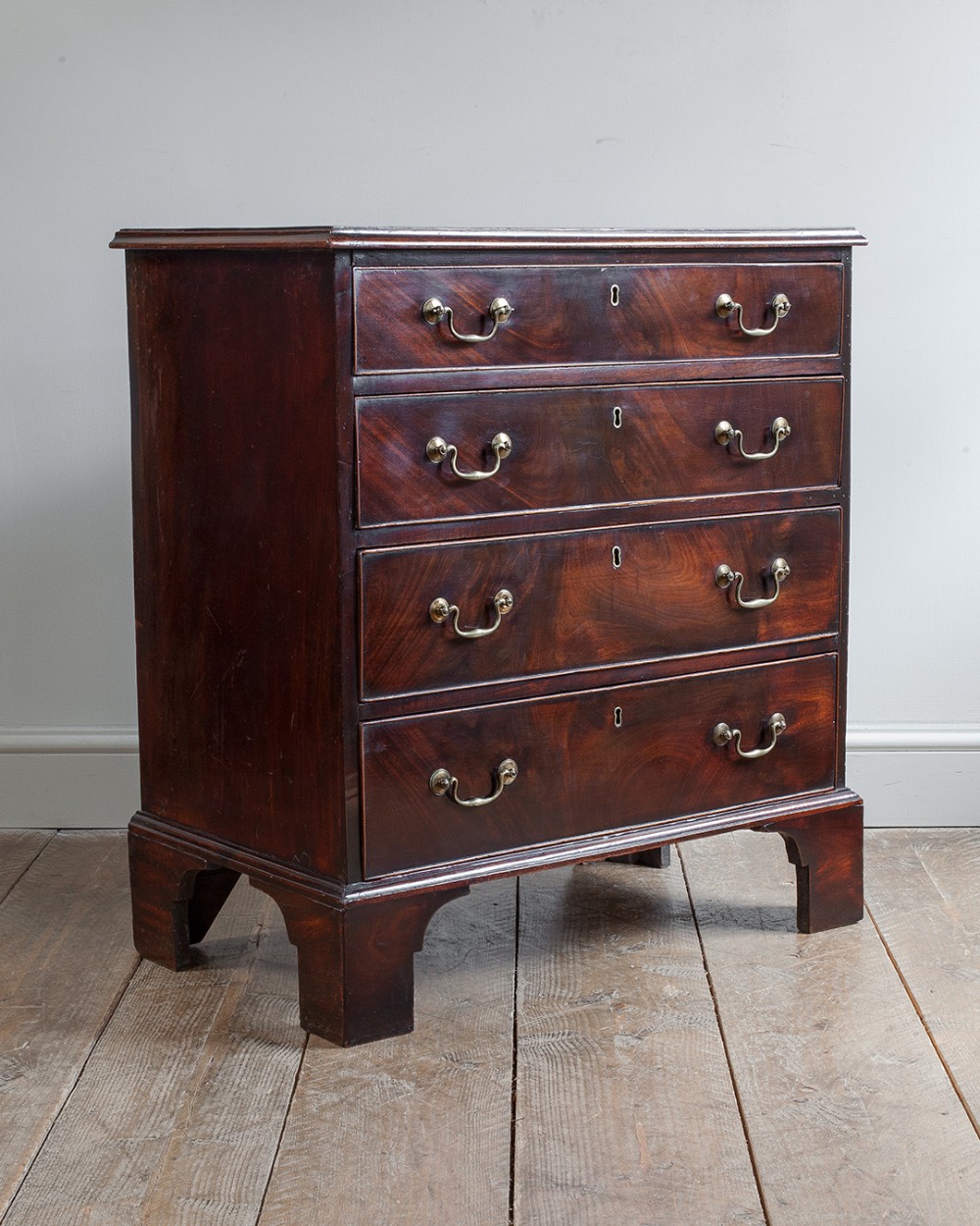 A Georgian mahogany chest featuring four graduated drawers with brass swan-neck handles, raised on straight bracket feet.