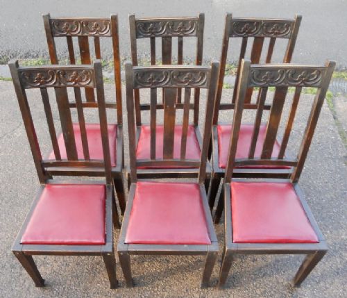 fig 1. A set of six dark beech Art Nouveau highback dining chairs featuring carved crest rails, vertical slatted backs, and red upholstered seats.