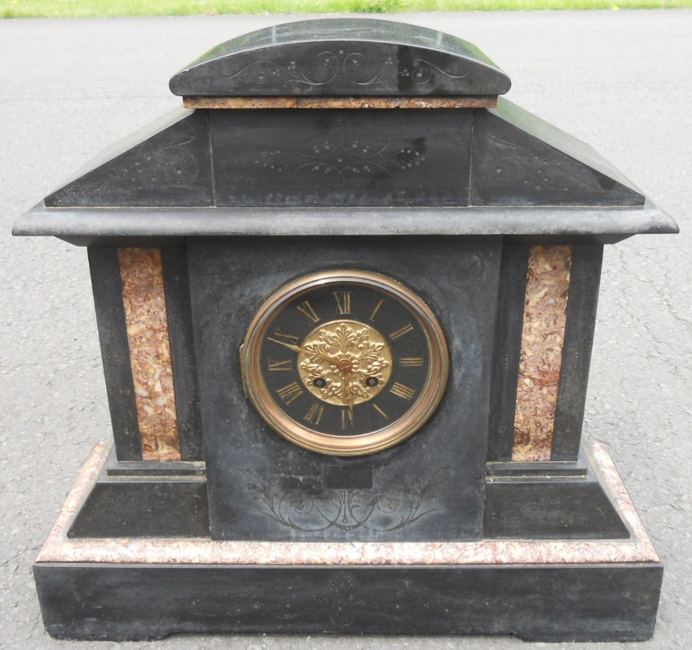Victorian black slate and pink marble mantel clock featuring an architectural shape and a gilded brass dial.