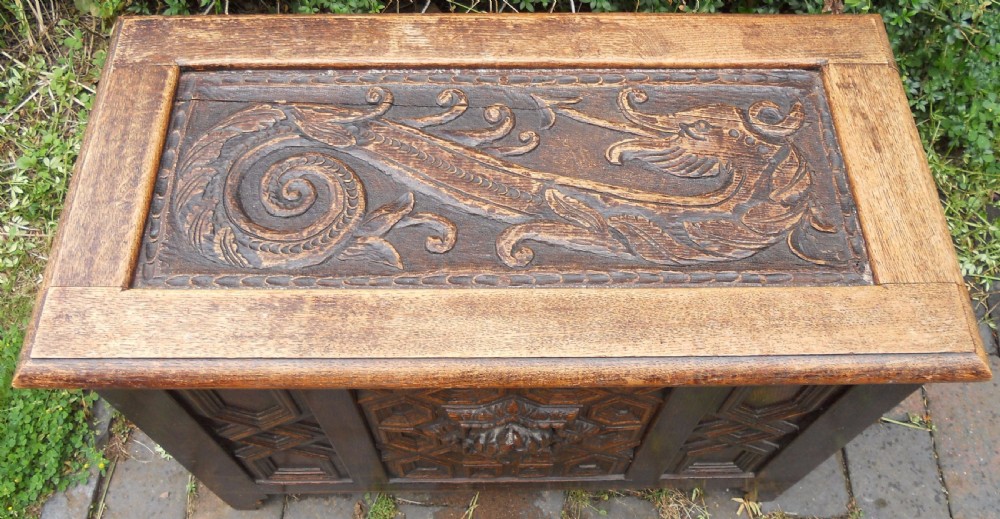 A rectangular Victorian carved oak blanket chest featuring a central carved face mask surrounded by geometric panel mouldings. View III