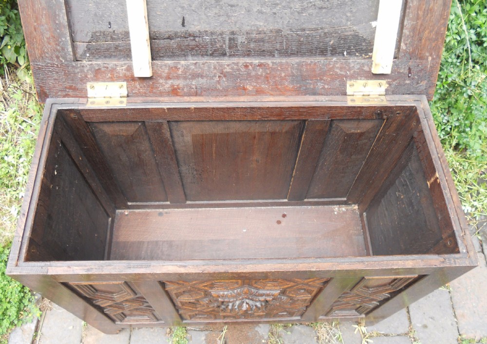 A rectangular Victorian carved oak blanket chest featuring a central carved face mask surrounded by geometric panel mouldings. View X