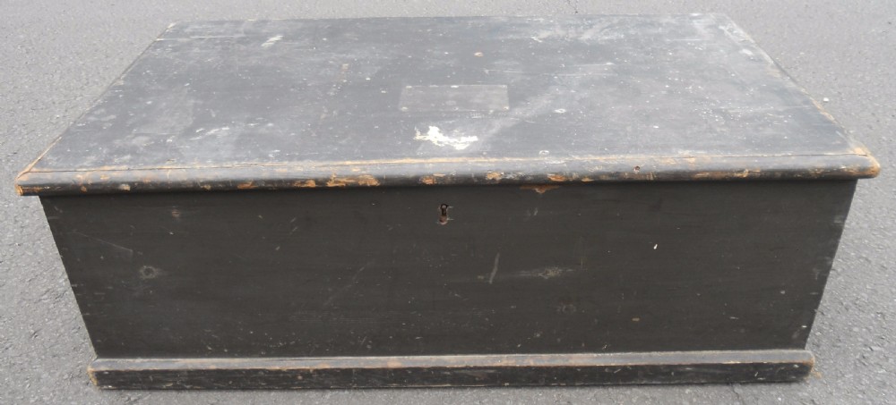 A rectangular black painted Victorian pine travelling box with a keyhole on the front panel and a metal plaque on the lid.