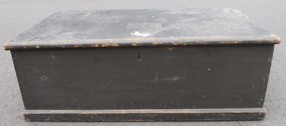 A rectangular black painted Victorian pine travelling box with a keyhole on the front panel and a metal plaque on the lid. View II