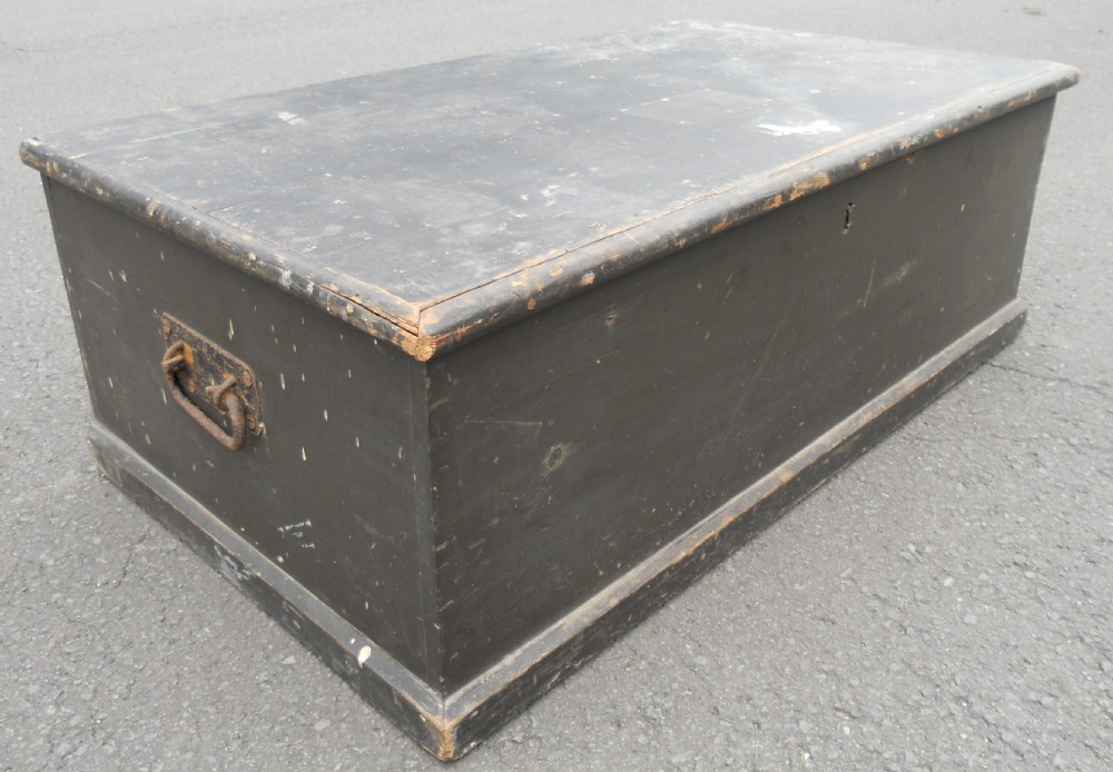 A rectangular black painted Victorian pine travelling box with a keyhole on the front panel and a metal plaque on the lid. View IV