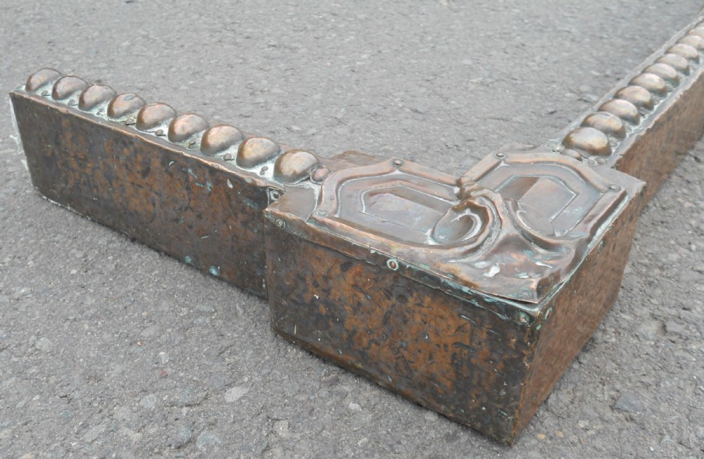An Arts and Crafts copper fireside kerb featuring a raised arched centre, decorative studding along the upper edge, and ornate corner brackets. View IX