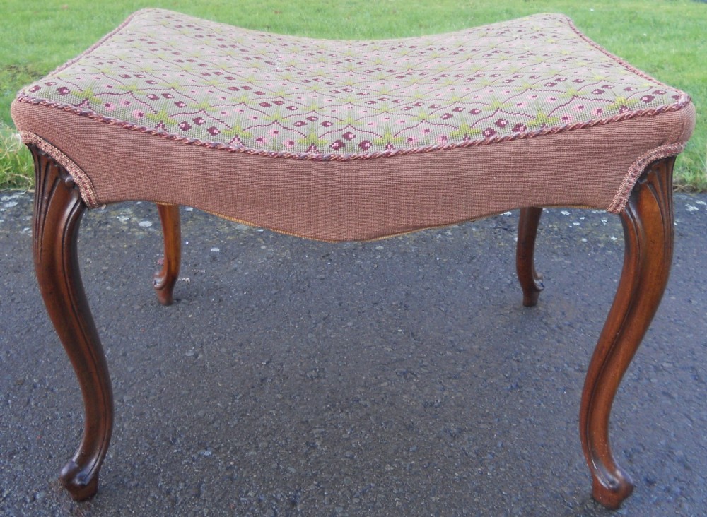 A Victorian walnut dressing stool featuring a concave seat with geometric tapestry fabric supported by four carved cabriole legs.