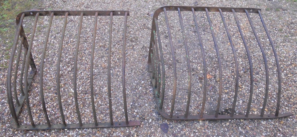 A pair of Victorian dark wrought iron curved hay racks featuring vertical metal bars and mounting plates. View II