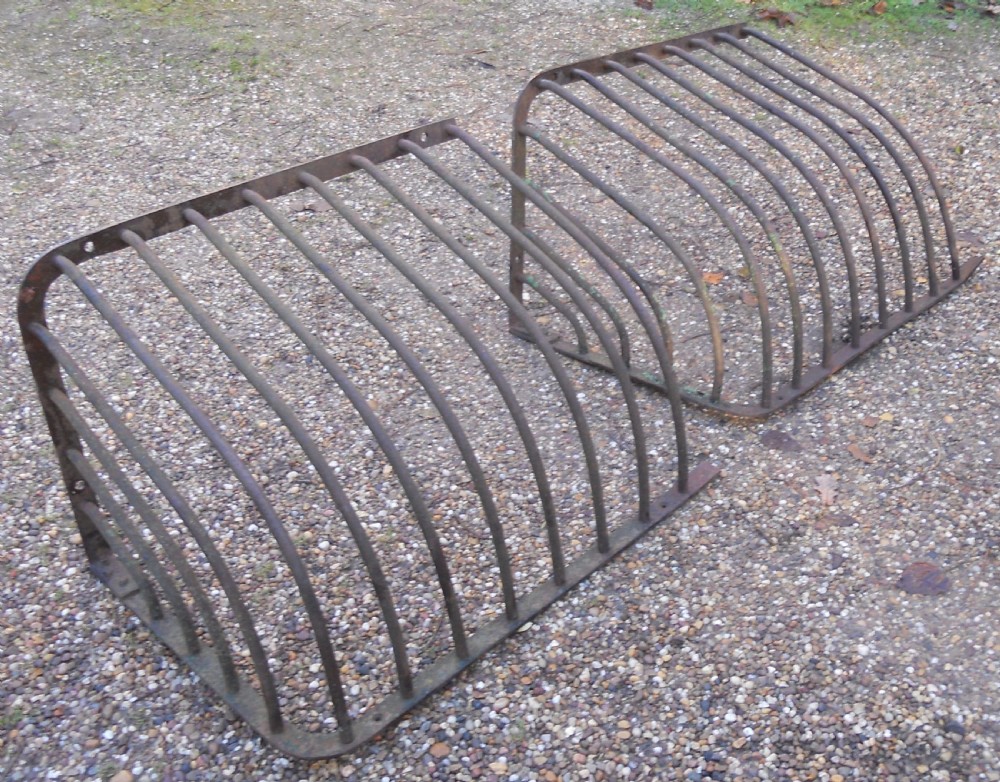A pair of Victorian dark wrought iron curved hay racks featuring vertical metal bars and mounting plates. View III