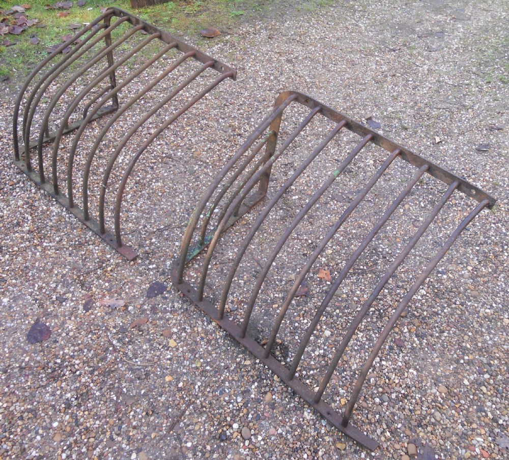 A pair of Victorian dark wrought iron curved hay racks featuring vertical metal bars and mounting plates. View V