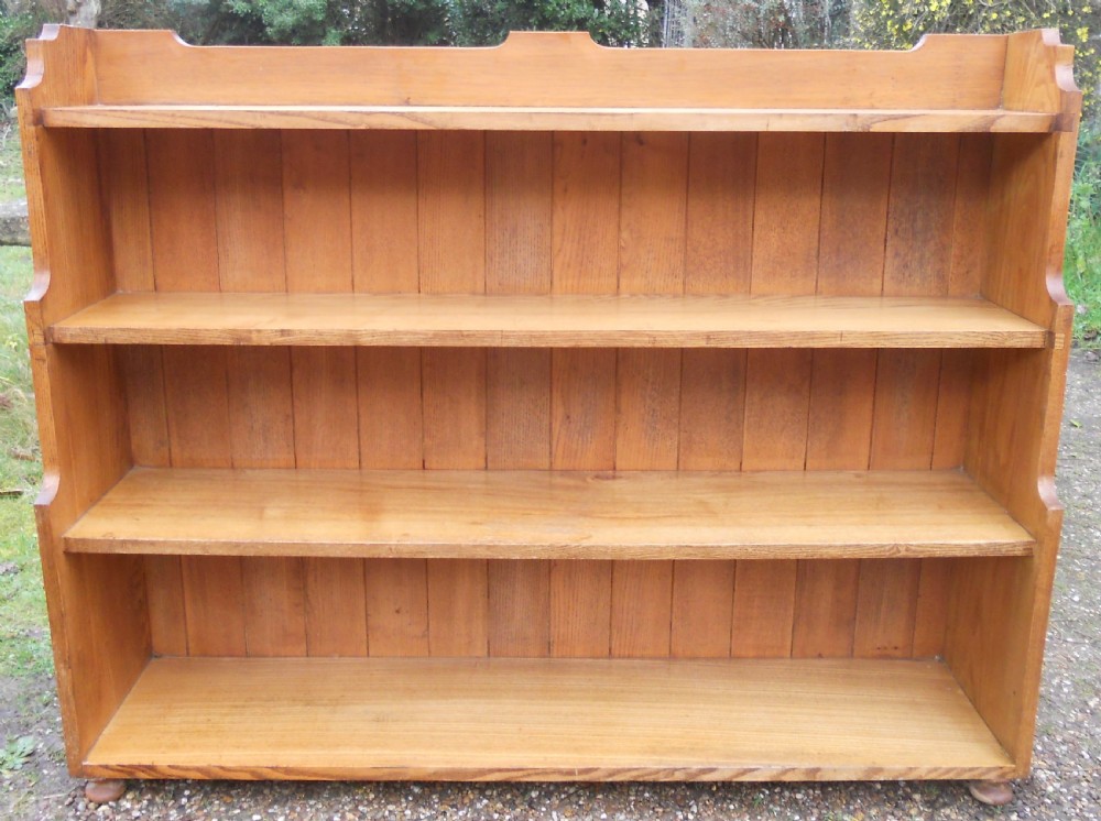 An Edwardian solid oak open waterfall bookcase featuring four tiers with stepped sides, a plank back, and a shaped top gallery. View II