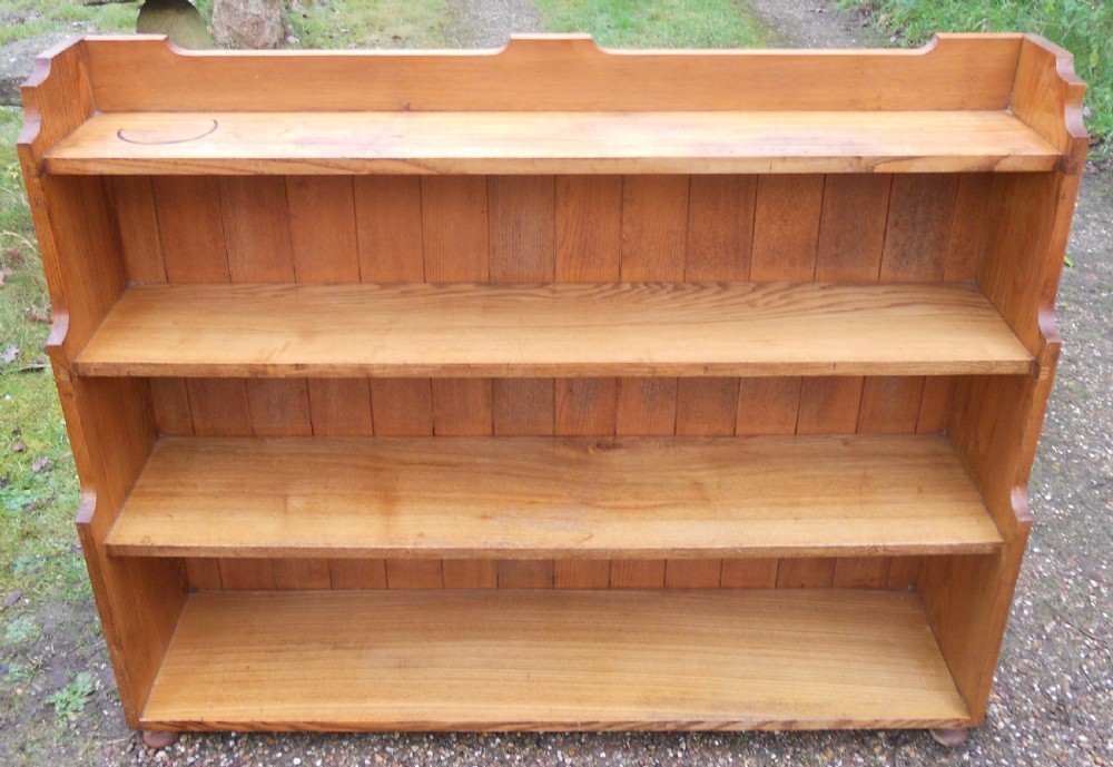 An Edwardian solid oak open waterfall bookcase featuring four tiers with stepped sides, a plank back, and a shaped top gallery. View III