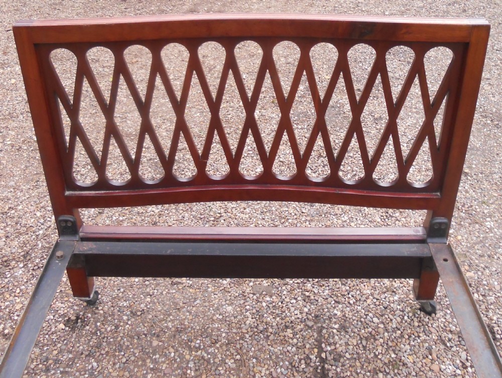 An Edwardian mahogany single bed frame featuring a lattice fretwork headboard and footboard on brass castors. View VIII