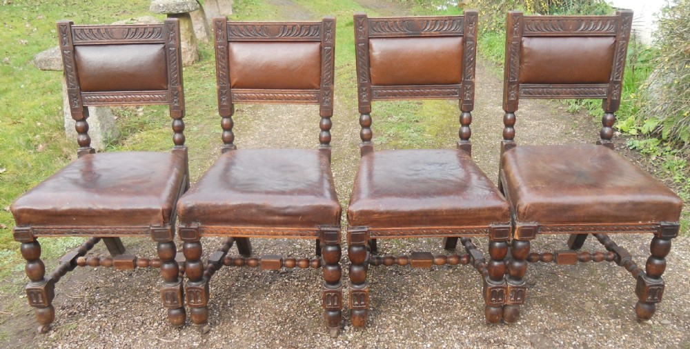A set of four antique dark oak dining chairs featuring carved backrests, turned legs, and brown leather upholstered seats. View III