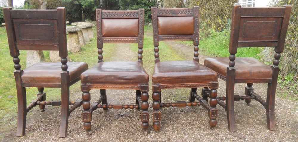 A set of four antique dark oak dining chairs featuring carved backrests, turned legs, and brown leather upholstered seats. View VII