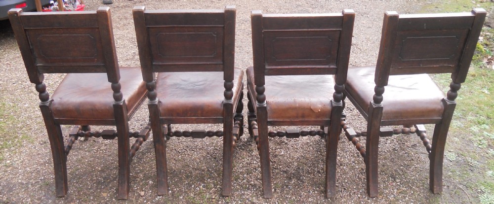 A set of four antique dark oak dining chairs featuring carved backrests, turned legs, and brown leather upholstered seats. View IX