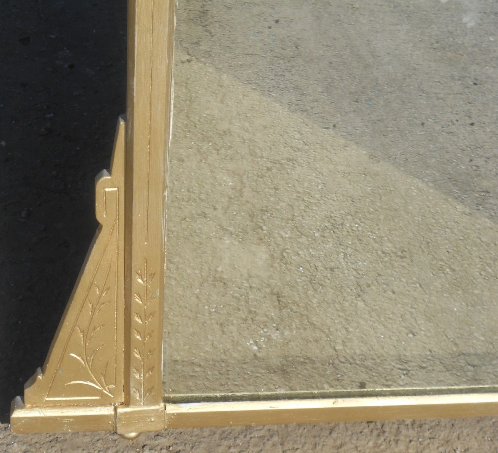 An Aesthetic Movement giltwood overmantel mirror featuring incised botanical carving, linear details, side bracket supports, and a pediment crest. View IV