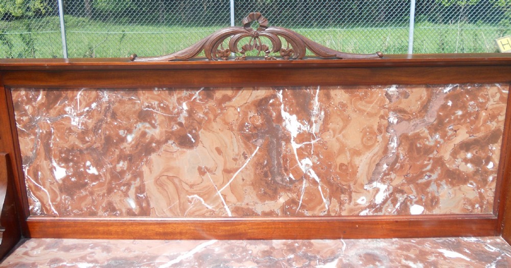 An Edwardian mahogany chest of drawers featuring a variegated red marble top, brass drop handles, and tapered legs on castors. View XIII