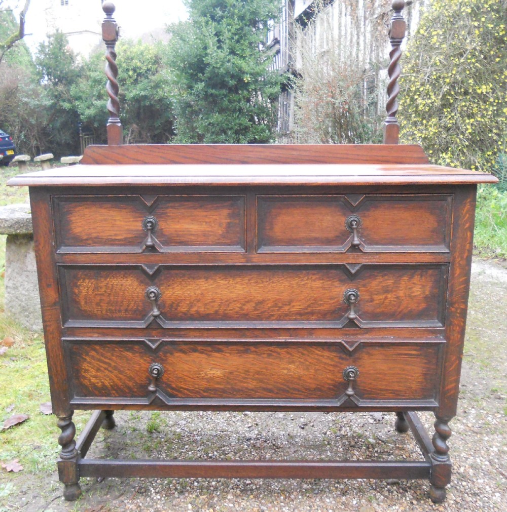 An antique dark oak dressing table with an arched swivel mirror, barley twist supports, and three drawers featuring geometric moulding. View V