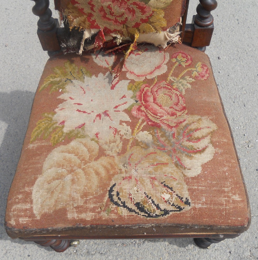 A Victorian carved walnut nursing chair with barley twist uprights, a carved cresting rail, turned front legs on castors, and floral needlepoint upholstery. View III