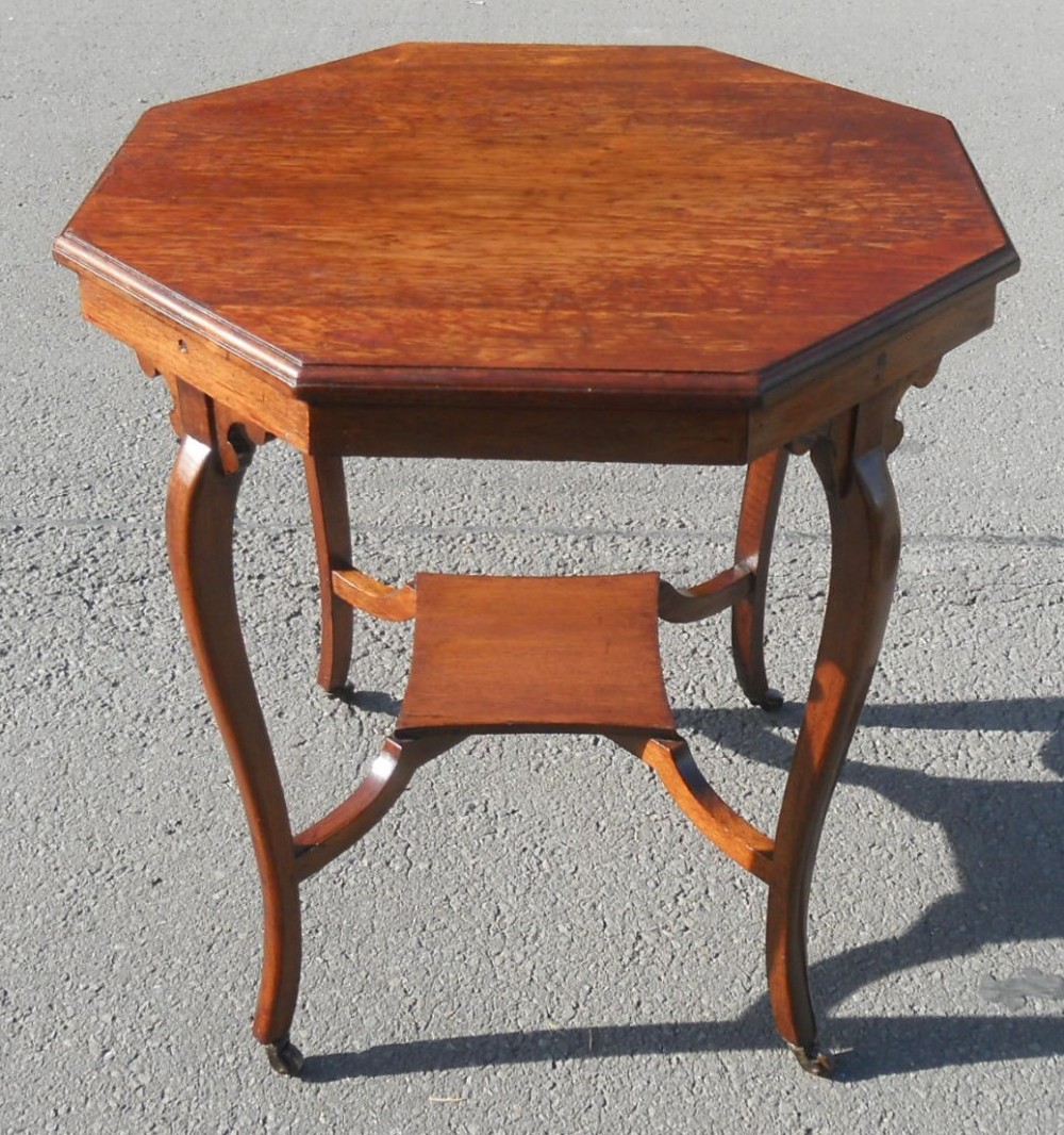 An Edwardian mahogany octagonal centre table featuring cabriole legs, brass castors, and a lower square undertier shelf.