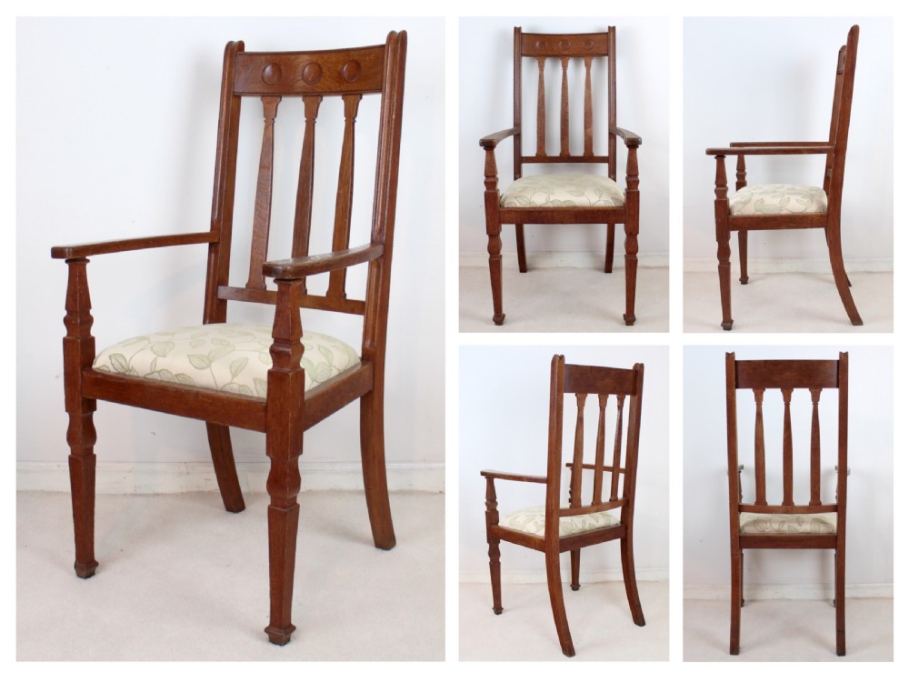 A pair of medium brown oak Arts and Crafts armchairs with carved circular back details, vertical splats, turned front legs, and light-coloured patterned seat cushions. View II