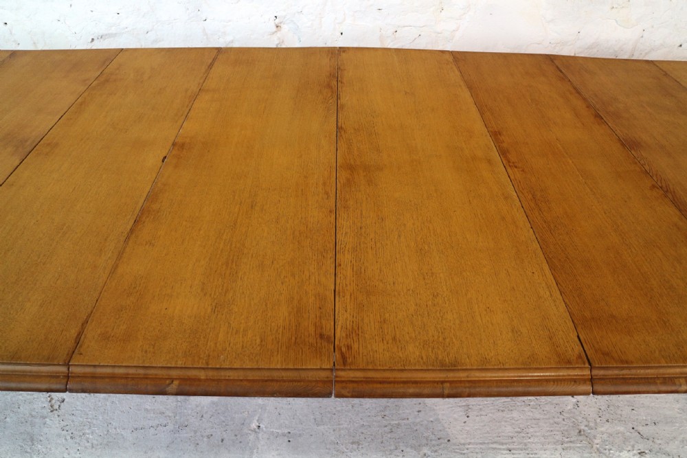 An extended early Victorian oak dining table featuring turned fluted legs set on brass castors with rounded corners and removable insert leaves. View X