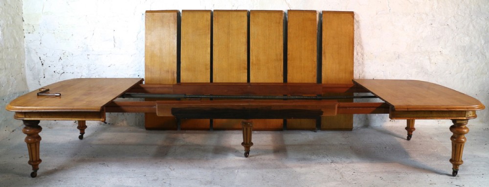 An extended early Victorian oak dining table featuring turned fluted legs set on brass castors with rounded corners and removable insert leaves. View XI