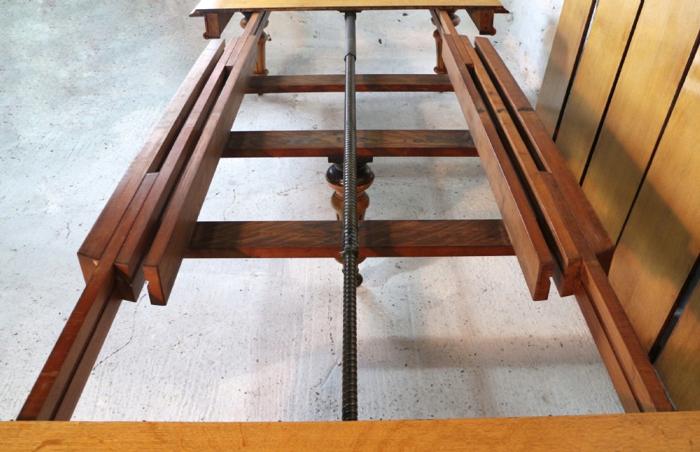 An extended early Victorian oak dining table featuring turned fluted legs set on brass castors with rounded corners and removable insert leaves. View XII