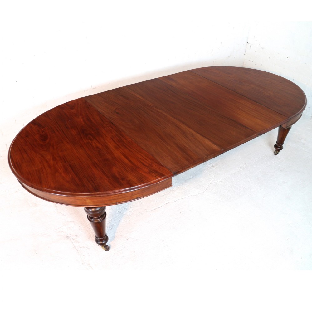 An extended Victorian Cuban mahogany dining table with rounded ends, turned legs, and brass castors.