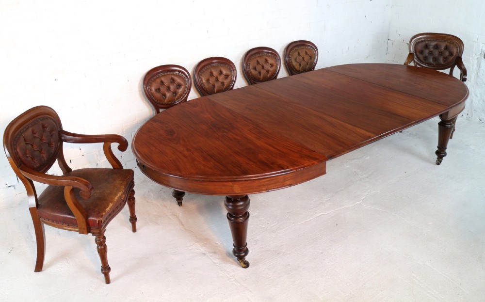 An extended Victorian Cuban mahogany dining table with rounded ends, turned legs, and brass castors. View II