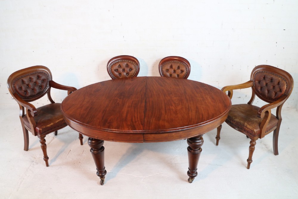 An extended Victorian Cuban mahogany dining table with rounded ends, turned legs, and brass castors. View III
