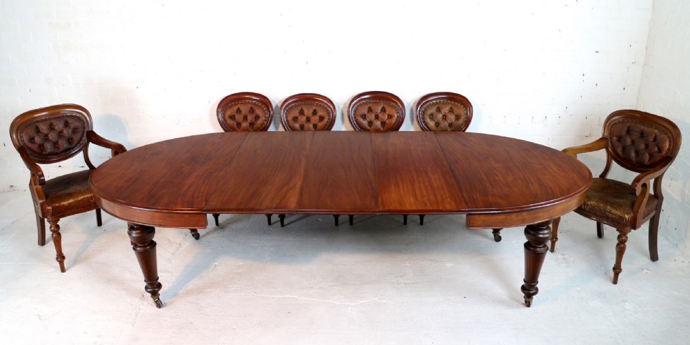 An extended Victorian Cuban mahogany dining table with rounded ends, turned legs, and brass castors. View VII