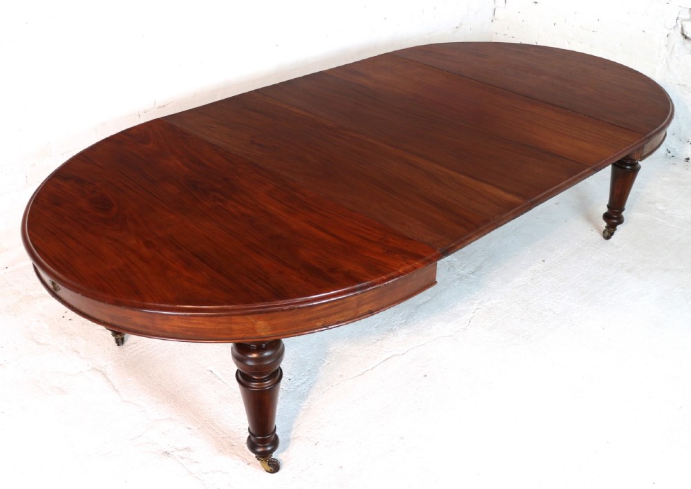 An extended Victorian Cuban mahogany dining table with rounded ends, turned legs, and brass castors. View VIII