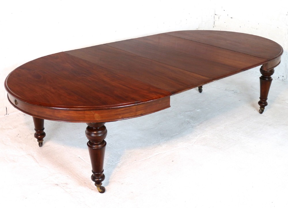An extended Victorian Cuban mahogany dining table with rounded ends, turned legs, and brass castors. View IX