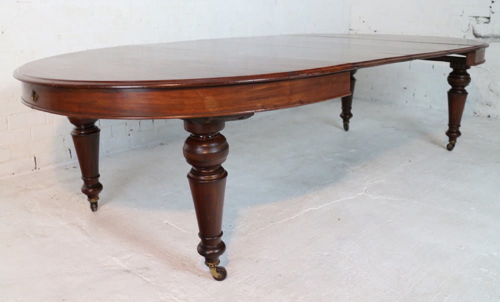 An extended Victorian Cuban mahogany dining table with rounded ends, turned legs, and brass castors. View X