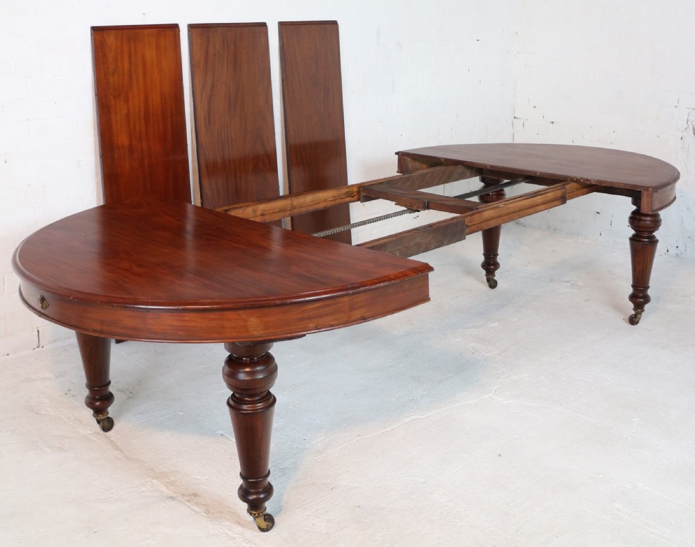 An extended Victorian Cuban mahogany dining table with rounded ends, turned legs, and brass castors. View XI