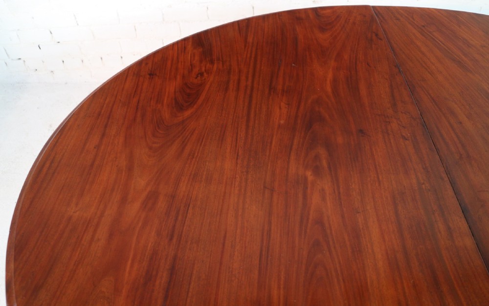 An extended Victorian Cuban mahogany dining table with rounded ends, turned legs, and brass castors. View XIII