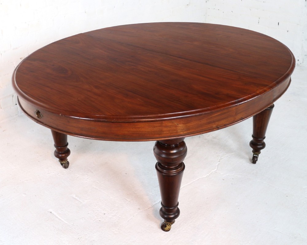 An extended Victorian Cuban mahogany dining table with rounded ends, turned legs, and brass castors. View XIV