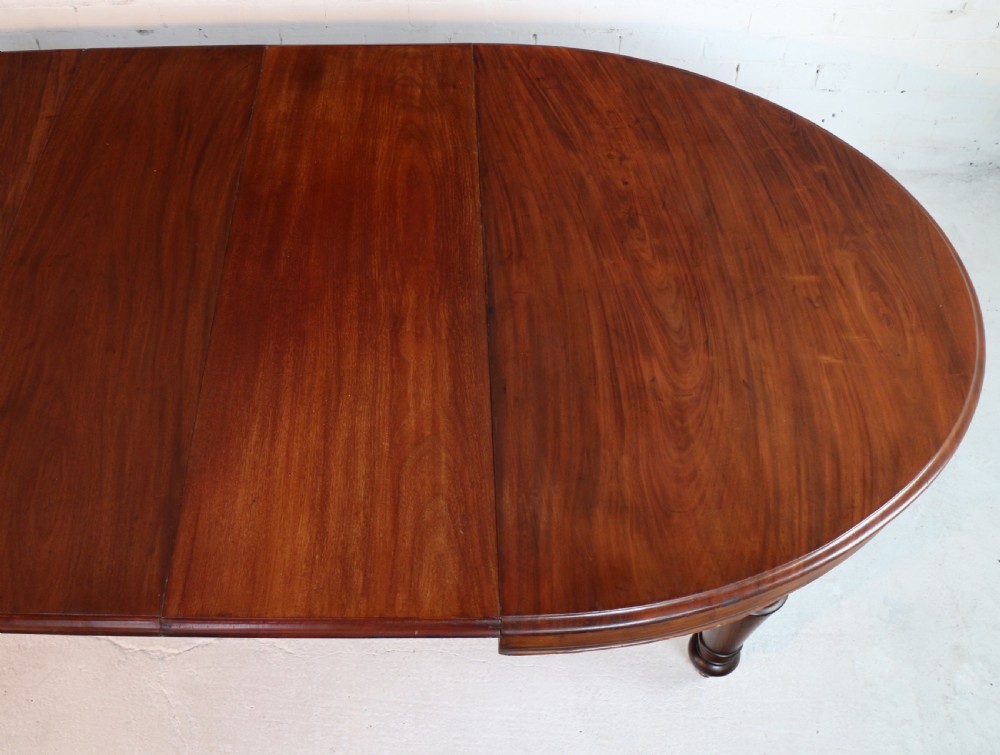 An extended Victorian Cuban mahogany dining table with rounded ends, turned legs, and brass castors. View XVI