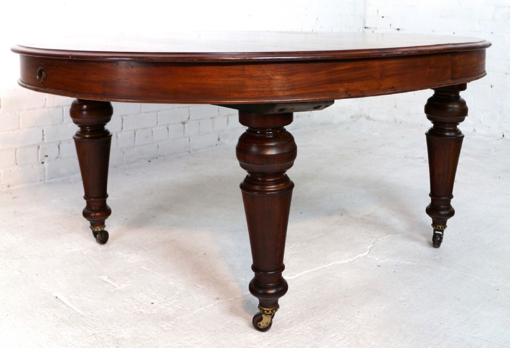 An extended Victorian Cuban mahogany dining table with rounded ends, turned legs, and brass castors. View XVII