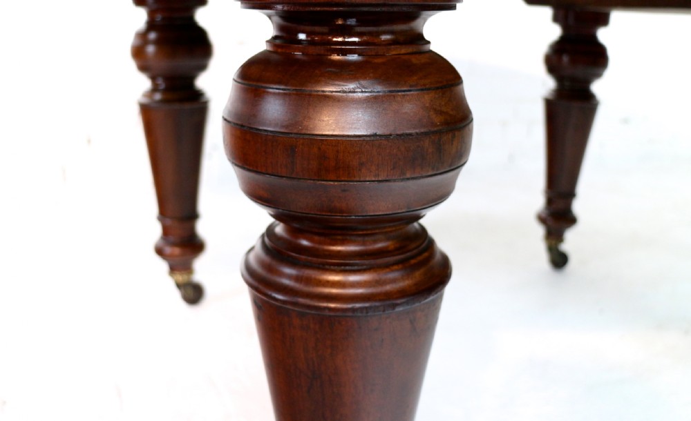 An extended Victorian Cuban mahogany dining table with rounded ends, turned legs, and brass castors. View XIX