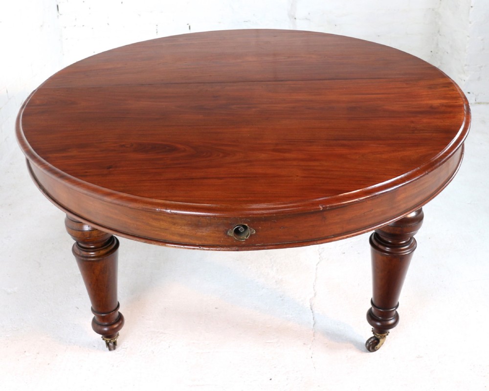 An extended Victorian Cuban mahogany dining table with rounded ends, turned legs, and brass castors. View XX