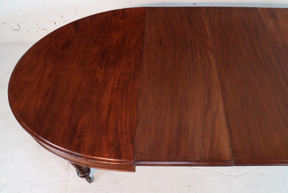 An extended Victorian Cuban mahogany dining table with rounded ends, turned legs, and brass castors. View XXI