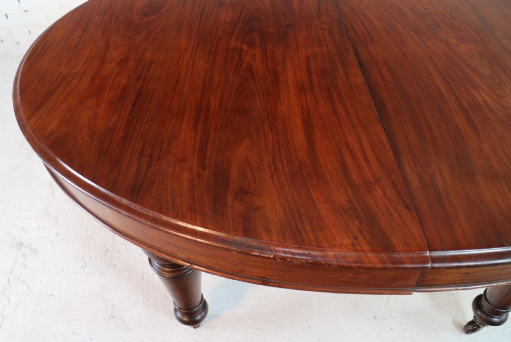 An extended Victorian Cuban mahogany dining table with rounded ends, turned legs, and brass castors. View XXIII