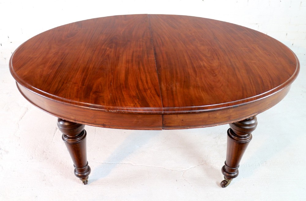 An extended Victorian Cuban mahogany dining table with rounded ends, turned legs, and brass castors. View XXV